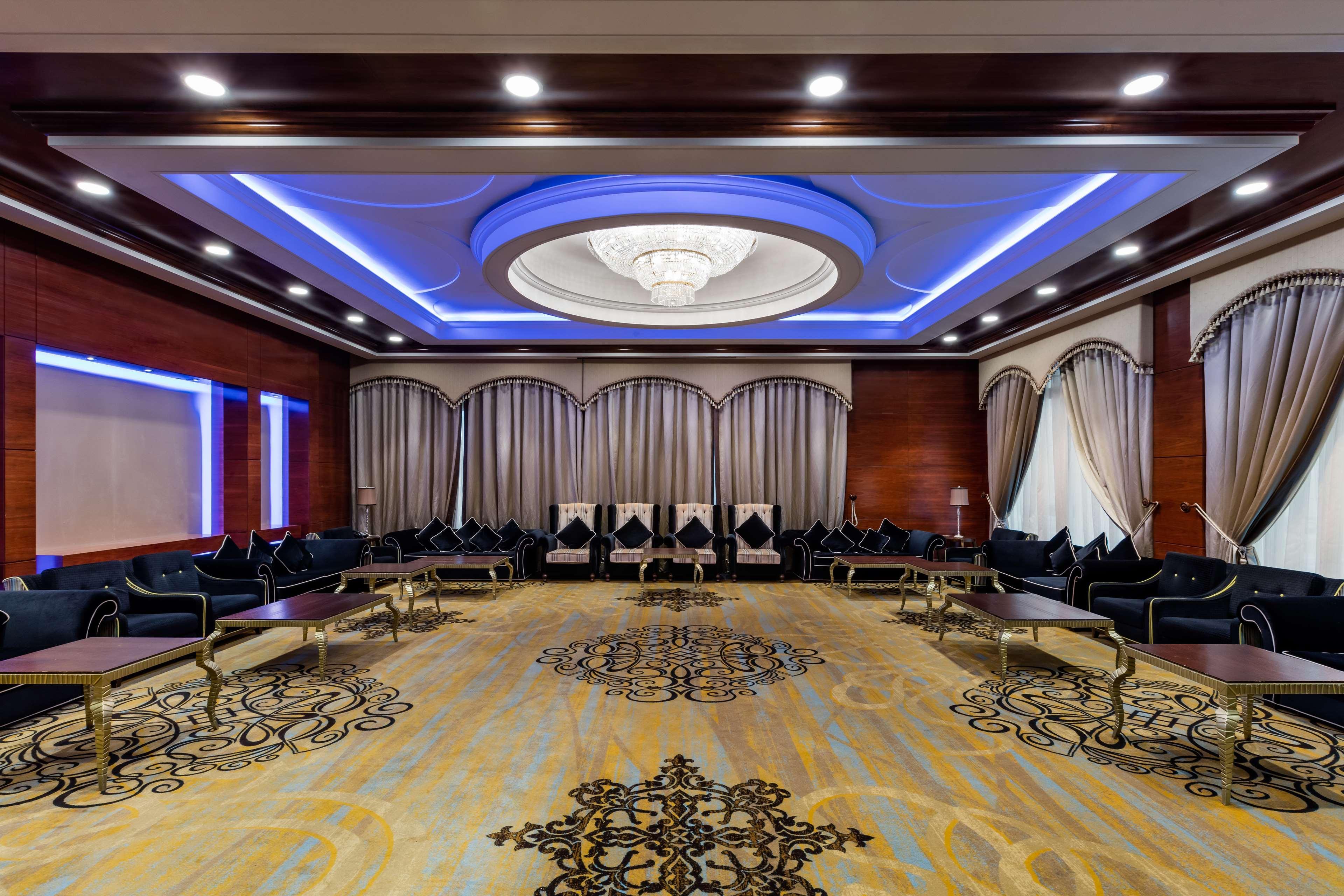 The Diplomat Radisson Blu Hotel Residence & Spa Manama Exterior photo The photo shows an elegant interior space, likely a conference room or banquet hall. It features a spacious layout with a decorative carpet, and the walls are adorned with stylish curtains. The ceiling is highlighted with a decorative chandelier at t